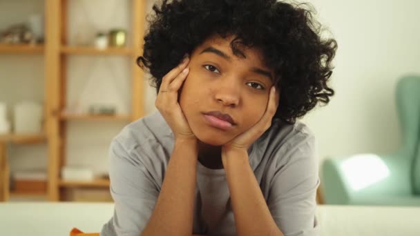 Afroameričanka smutná zamyšlená, zamyšlená, nemotivovaná dívka sedící doma na gauči. Mladá africká žena přemýšlející po dlouhém dni vypadá unaveně. Dívka cítí depresi uražený osamělý neklid zlomené srdce - Záběry, video
