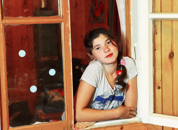 木製の窓の外を編むとプレティーンの美しい少女を見る - 写真・画像