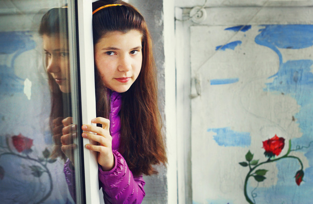 beautiful teen girl look out of the balcony window on the wall d - Zdjęcie, obraz