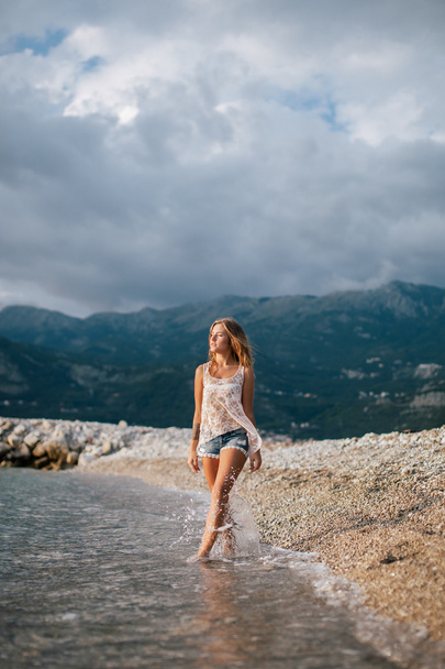 verträumte Mode Mädchen Spaziergang am Strand mit Bergen Hintergrund - Foto, Bild
