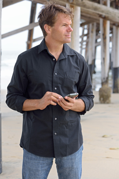 Hombre usando el teléfono inteligente en la playa
 - Foto, imagen
