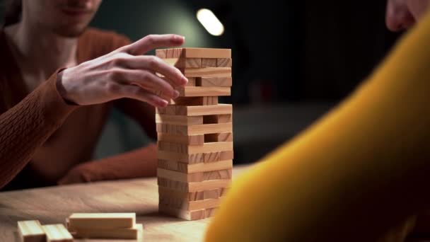 Vrienden genieten van een leuk spelletje Jenga thuis, vakkundig balanceren houten torenblokken met zorg en precisie. Kopieerruimte - Video