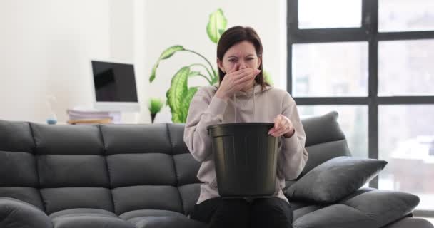 Young woman suffers from nausea at home. Food poisoning and bucket - Footage, Video