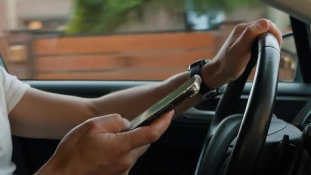 Autista utilizzando smartphone durante la guida di auto, distratto da messaggi sul suo telefono. Guida pericolosa di un veicolo, violazione delle regole del traffico - Filmati, video
