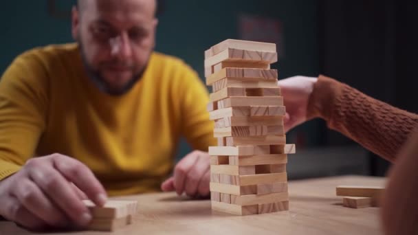 Spelers stapelen houten blokken in een uitdagend spel van precisie en strategie op een tafelblad. Kopieerruimte - Video