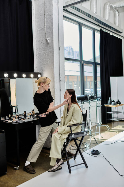 Woman sits in chair, facing mirror, next to stylist. - Photo, Image