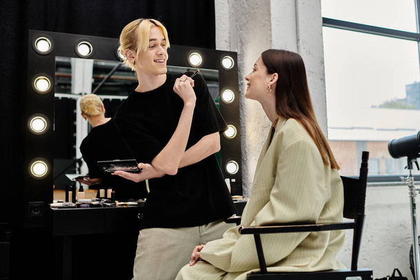 Una mujer siendo diseñada por un maquillador frente a un espejo. - Foto, imagen