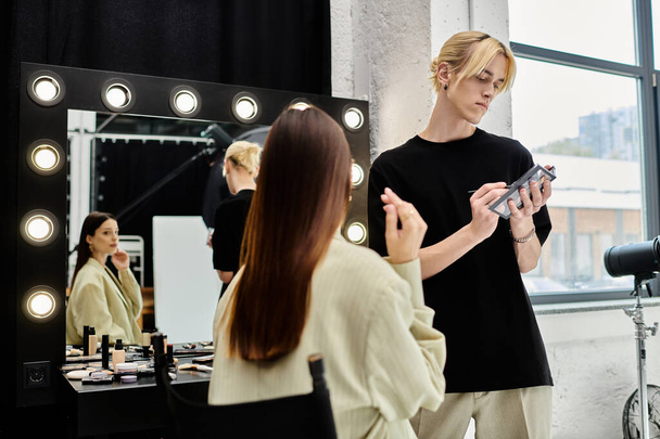 Μακριά μαλλιά γυναίκα να πάρει μακιγιάζ γίνεται από επαγγελματία καλλιτέχνη μπροστά από τον καθρέφτη. - Φωτογραφία, εικόνα
