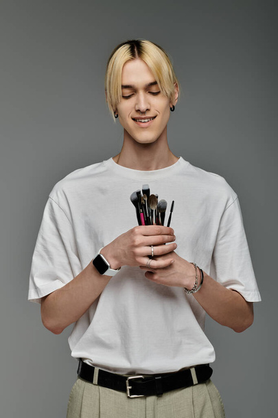 Mladý muž předvádění make-up štětce se stylem. - Fotografie, Obrázek
