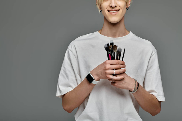 Man elegantly holds various brushes in a colorful display. - Photo, Image