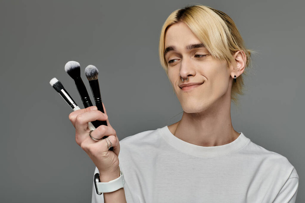 Man gracefully holds a bunch of makeup brushes. - Photo, Image