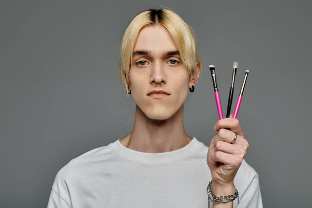 Stylish man proudly presents makeup brushes. - Photo, Image