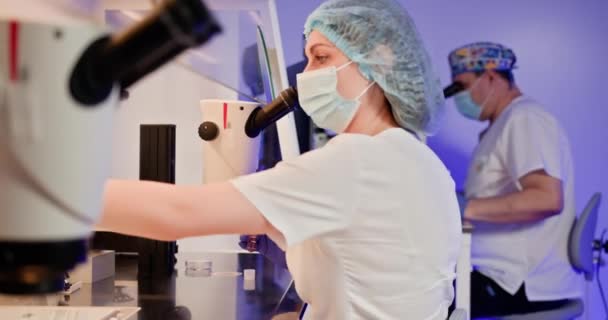 Zwei Embryologen in einem Labor, das künstliche Befruchtungen mit Mikroskopen und medizinischen Instrumenten durchführt. IVF-Verfahren im Gange für die Reproduktionswissenschaften und medizinische Forschung. Embryologe. - Filmmaterial, Video