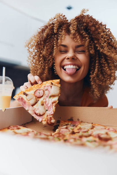 Happy woman holding slice of pizza in front of face in box, smiling - Foto, afbeelding