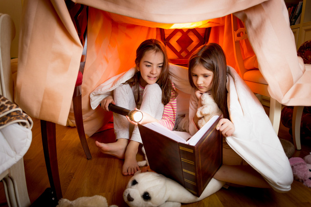 Dvě sestry sedí doma vyrobené z přikrývek a čtení knih - Fotografie, Obrázek