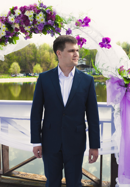 beau marié attendant la mariée sous arc floral lors de la cérémonie
 - Photo, image