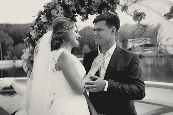 Monochrome portrait of happy bride and groom looking at each oth
 - Фото, изображение