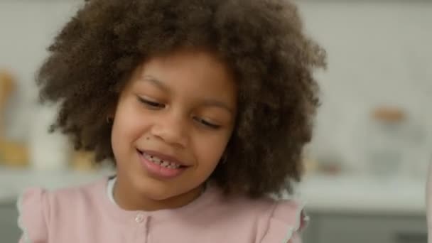 close-up cropped uitzicht gelukkig Afrikaans Amerikaans etnisch klein lachend meisje dochter geadopteerd kind adoptie kind voogdij glimlach baby dansen gek leuk dans met onherkenbare ouders in keuken koken - Video