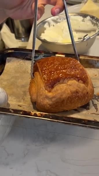 Frissen sült croissant tálcán egy pékségben, közelről. Süti croissant sütőben - Felvétel, videó