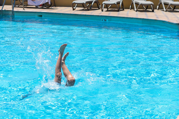 Child's legs poking out of the water of a swimming pool - Photo, Image