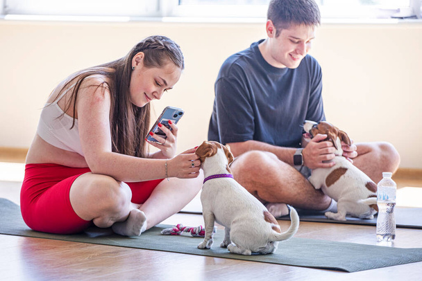 pareja feliz haciendo yoga junto con el pequeño cachorro Jack Russell Terrier. Estilo de vida saludable. Generación futura - Foto, imagen