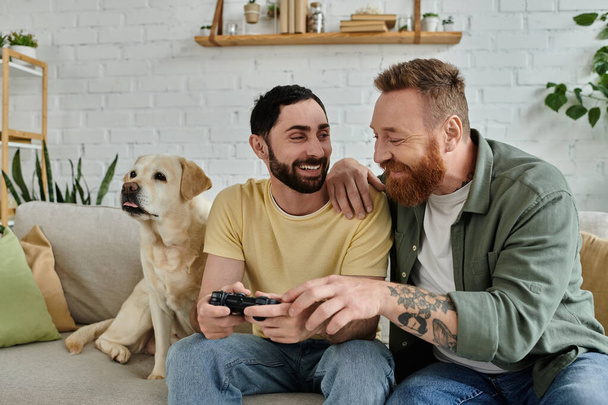 Homopari ja heidän koiransa nauttivat laatuajasta pelatessaan videopeliä sohvalla. - Valokuva, kuva