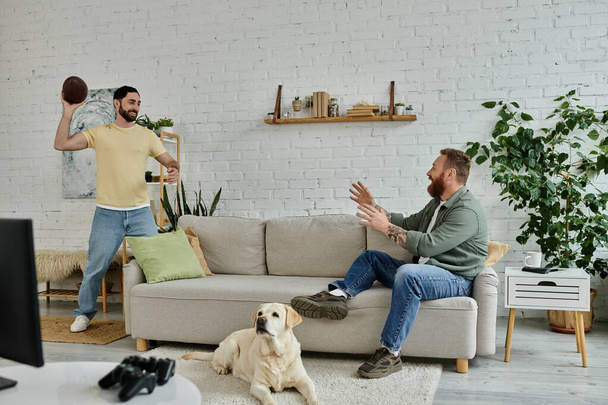 Homem barbudo e cão assistir esportes no sofá na acolhedora sala de estar. - Foto, Imagem