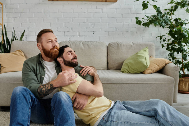 Двоє бородатих чоловіків відпочивають на дивані, насолоджуючись компанією один одного в теплій вітальні. - Фото, зображення
