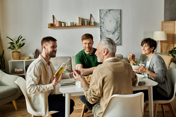 Ein schwules Paar genießt zu Hause das Abendessen mit den Eltern. - Foto, Bild