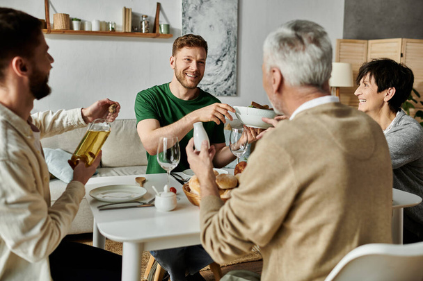 Una pareja gay se sienta en una mesa con sus padres, compartiendo una comida y disfrutando de la compañía de los demás. - Foto, Imagen