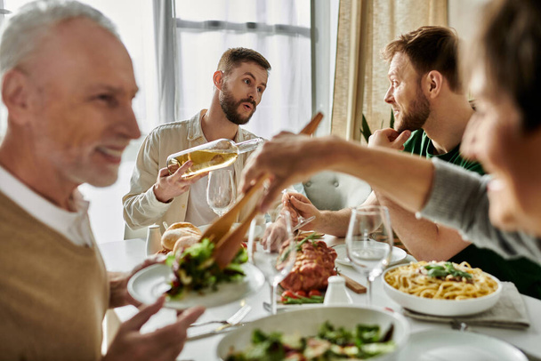 Ένα γκέι ζευγάρι μοιράζεται ένα γεύμα με τις οικογένειές τους στο σπίτι.. - Φωτογραφία, εικόνα