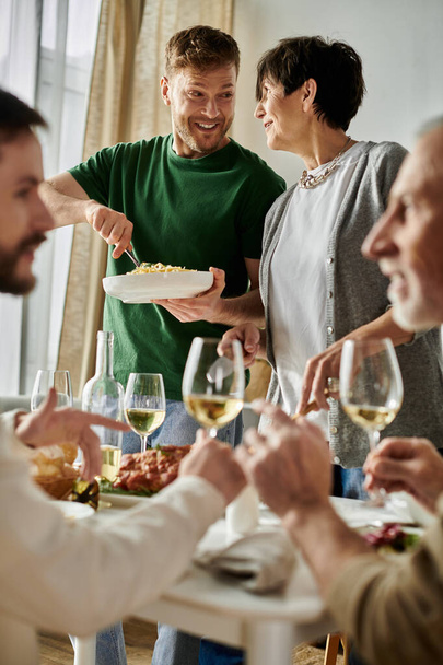 Um casal gay desfruta de uma refeição com sua família em casa. - Foto, Imagem
