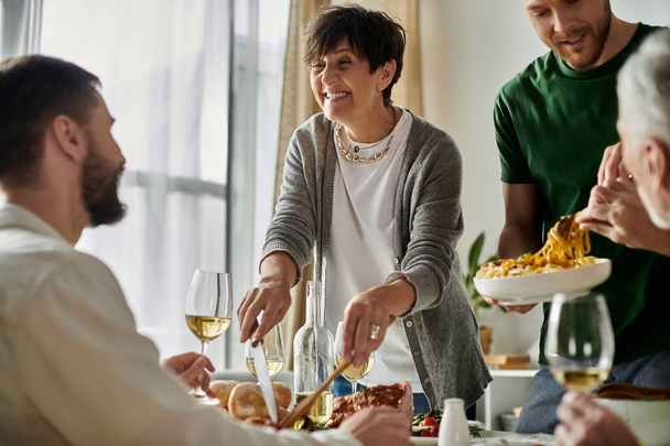 Una pareja gay disfruta de una comida casera con su familia, llena de sonrisas y conversación. - Foto, imagen