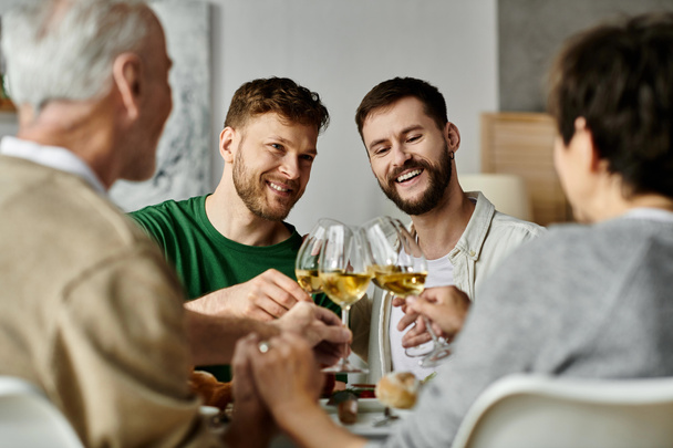 Ein schwules Paar erhebt bei einem festlichen Abendessen zu Hause ein Glas mit den Eltern. - Foto, Bild