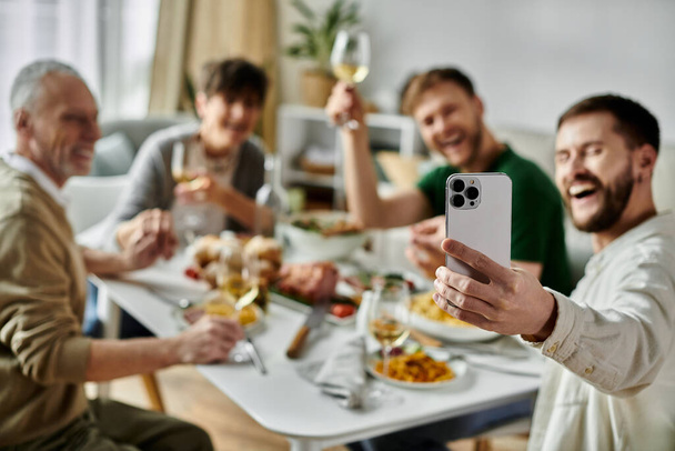 Un couple gay prend un selfie avec sa famille pendant un repas. - Photo, image