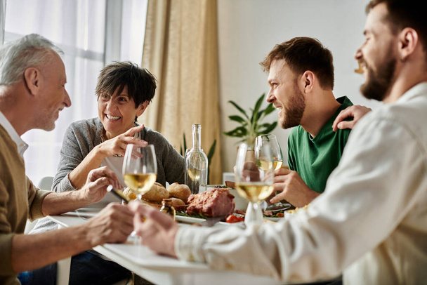 Ένα γκέι ζευγάρι απολαμβάνει το δείπνο με τους γονείς στο σπίτι.. - Φωτογραφία, εικόνα