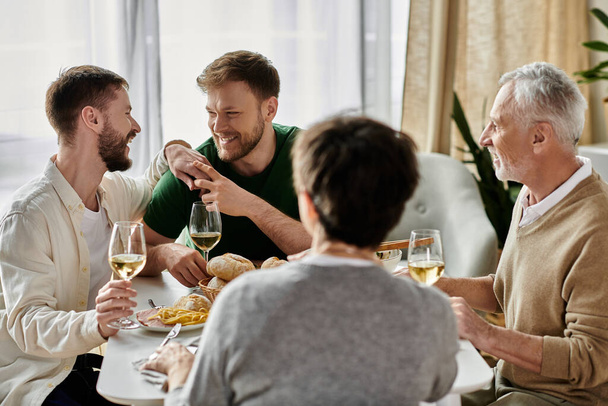 Ένα γκέι ζευγάρι απολαμβάνει ένα γεύμα με τους γονείς του στο σπίτι. - Φωτογραφία, εικόνα