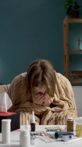 Une femme présentant des symptômes de grippe se couvre le visage, entourée de médicaments, se sentant mal et épuisée - Séquence, vidéo