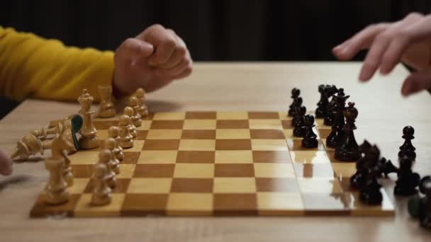 Close-up of two men playing chess sitting at a table at home. Leisure and board games concept - Footage, Video