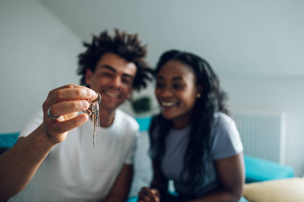Przepełniona radością afrykańska para małżeńska pokazująca klucze do swojego nowego mieszkania, które kupiła. Nowe mieszkanie i hipoteka. Skup się na kluczach.. - Zdjęcie, obraz