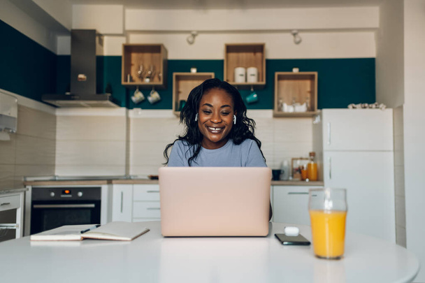 Nuori afrikkalainen amerikkalainen yrittäjä nainen työskentelee uuden projektin työskennellessään kotona keittiössä. Startup-yritykset ja uusi mobiiliteknologia. - Valokuva, kuva
