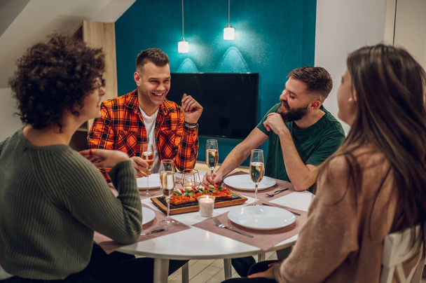 Vidám, boldog baráti társaság, akik otthon vacsoráznak. Baráti találkozó. Egy csapat boldog ember beszél és eszik. Boldog barátok, finom ételek és italok.. - Fotó, kép