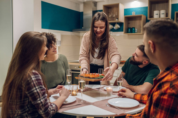 Cieszymy się kolacją z przyjaciółmi. Koncepcja przyjaźni z tysiącletnimi ludźmi cieszącymi się kolacją w domu i jedzącymi razem podczas rozmowy. - Zdjęcie, obraz