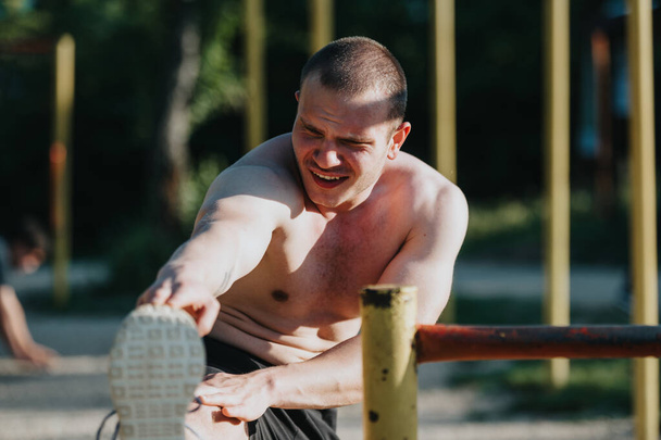 Tişörtsüz bir adam parkta egzersiz yapıyor. Güneşin altında spor yapıyor ve spor yapıyor.. - Fotoğraf, Görsel