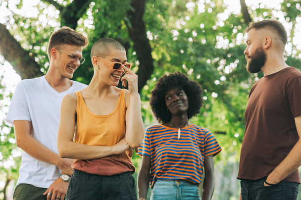 Porträt einer multikulturellen Gruppe von Hipster-Freunden, die in einem Park stehen und im Sommerurlaub Zeit miteinander verbringen. Jugendliche haben Spaß und verbringen schöne Zeit gemeinsam im Stadtpark. - Foto, Bild