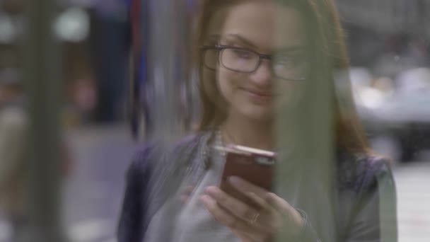Młoda biała kobieta używająca smartfona w mieście. Wysokiej jakości materiał 4k - Materiał filmowy, wideo