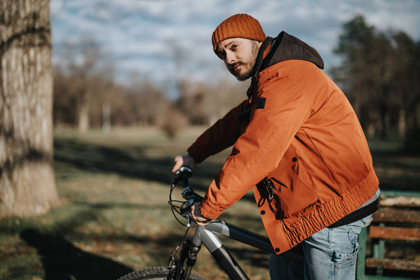 Homem elegante desfrutando de tempo livre ao ar livre com sua bicicleta, incorporando estilo de vida casual e moderno em um ambiente de parque. - Foto, Imagem