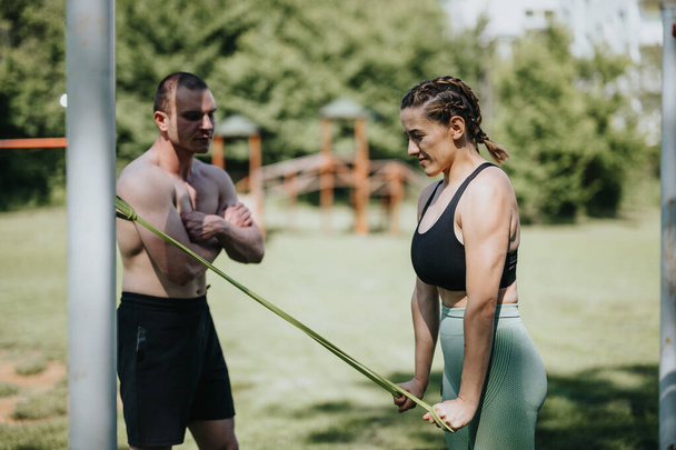 Dwóch entuzjastów fitness trenujących z taśmami oporowymi w zielonym parku, koncentrujących się na rutynach treningowych na świeżym powietrzu i zdrowym życiu. - Zdjęcie, obraz