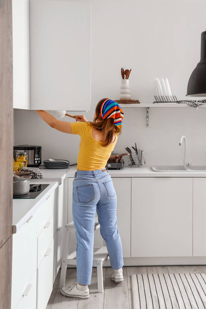 Junge Frau putzt Küche mit Staubwedel, Rückseite - Foto, Bild