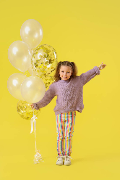 Ευτυχισμένο κοριτσάκι με μπαλόνια σε κίτρινο φόντο - Φωτογραφία, εικόνα